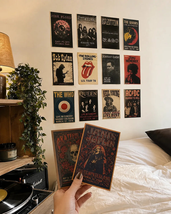 Customer holding two vintage 4×6 concert posters in a bedroom with a retro rock poster wall display.