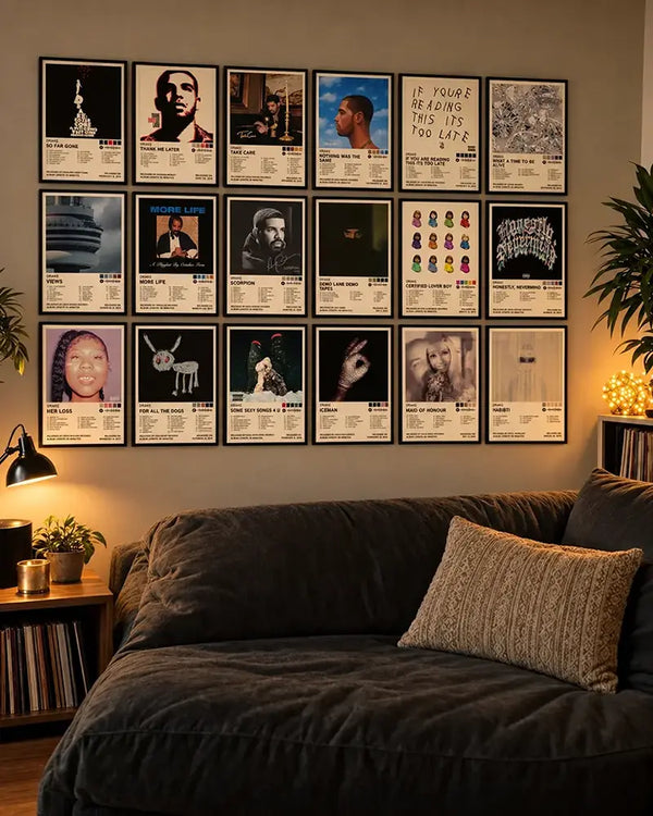 18 Drake album cover posters displayed in a framed gallery wall above a dark sofa in a warm, moody living room.