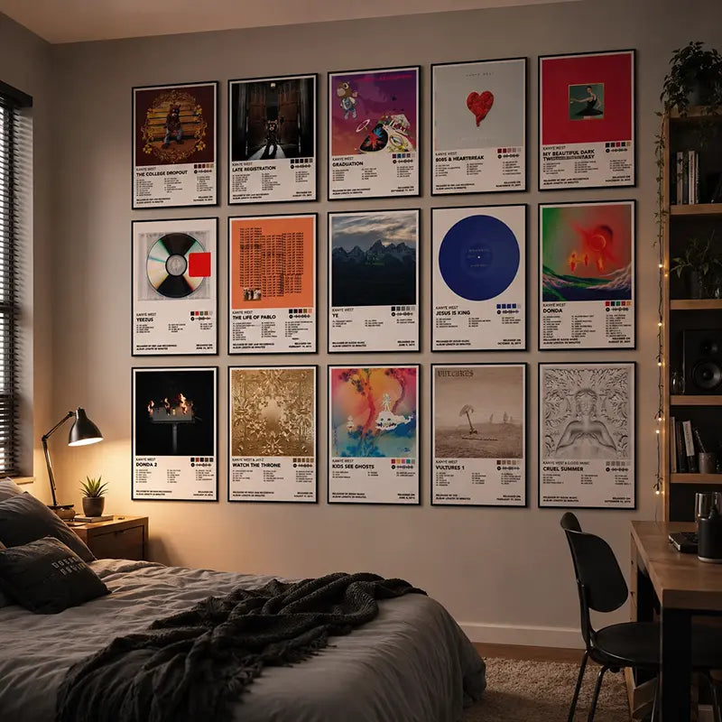 Fifteen framed Kanye West album cover posters arranged in a stylish grid above a bed in a cozy, warmly lit modern bedroom.